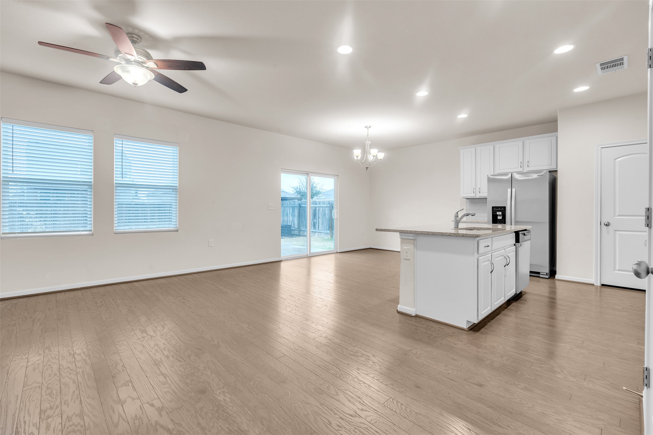 13014 Carswell Street Austin, TX 78754 - Photo 19 of 21 Kitchen with white cabinets, a chandelier, open floor plan, a kitchen island with sink, and stainless steel appliances