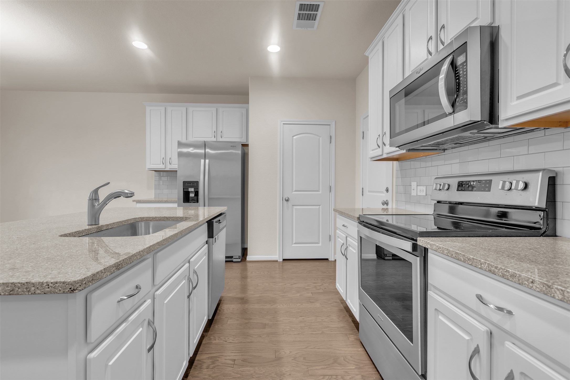 13014 Carswell Street Austin, TX 78754 - Photo 7 of 21 Kitchen featuring stainless steel appliances, white cabinetry, light wood-style flooring, an island with sink, and recessed lighting