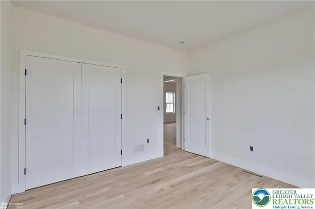 a view of an empty room with wooden floor and window