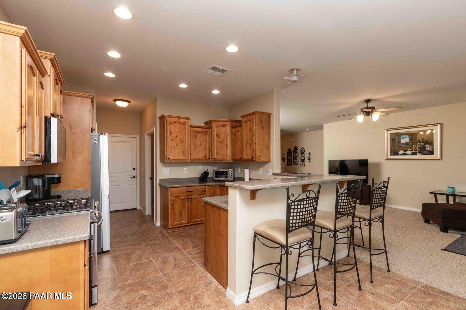 12933 Ponce Street Dewey, AZ 86327 - Photo 9 of 41 a kitchen with stainless steel appliances kitchen island granite countertop a stove a sink a refrigerator a dining table and chairs with wooden floor