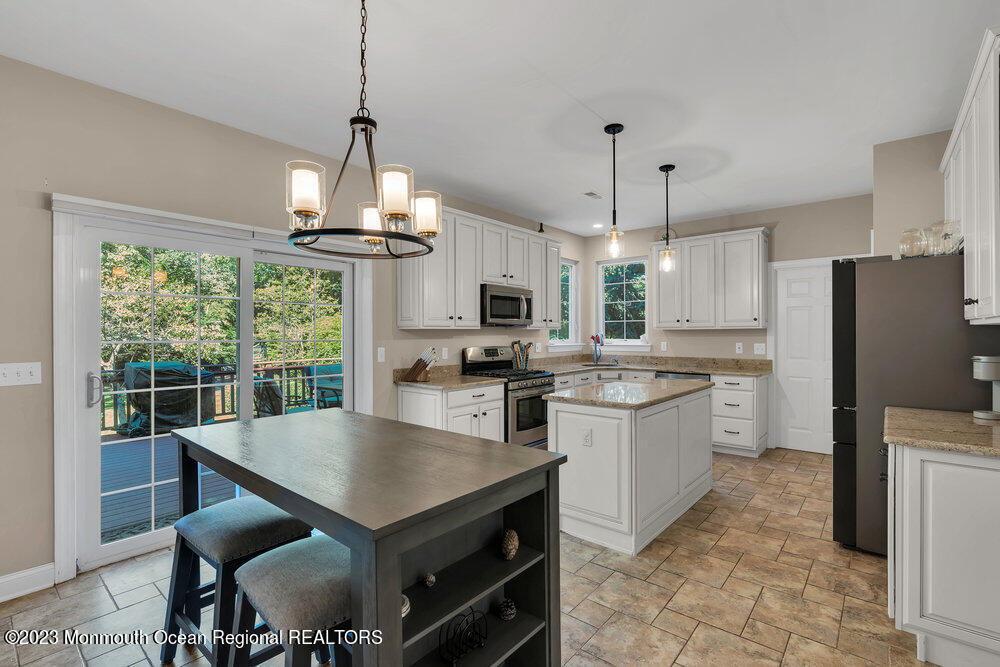 30 Erin Drive Jackson, NJ 08527 - Photo 28 of 105 a kitchen with stainless steel appliances granite countertop a stove a refrigerator a sink dishwasher a dining table and chairs with wooden floor