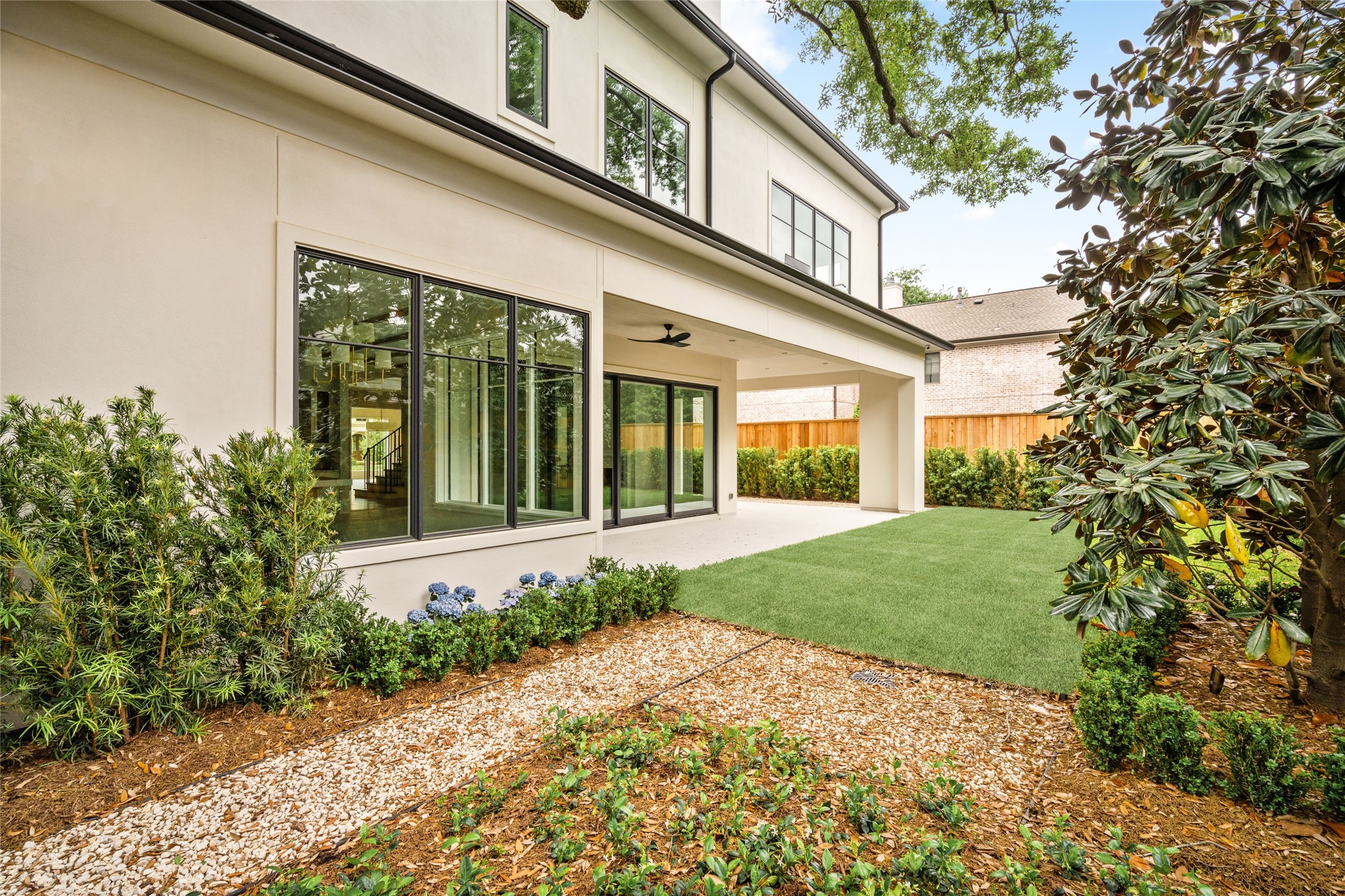 4006 Overbrook Lane Houston, TX 77027 - Photo 48 of 50 Alternate view of the backyard highlighting the home’s rear elevation, expansive windows, and covered patio.
