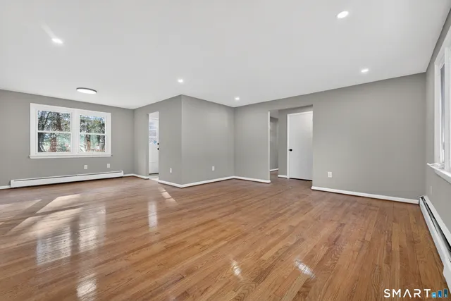 a view of an empty room with wooden floor and a window