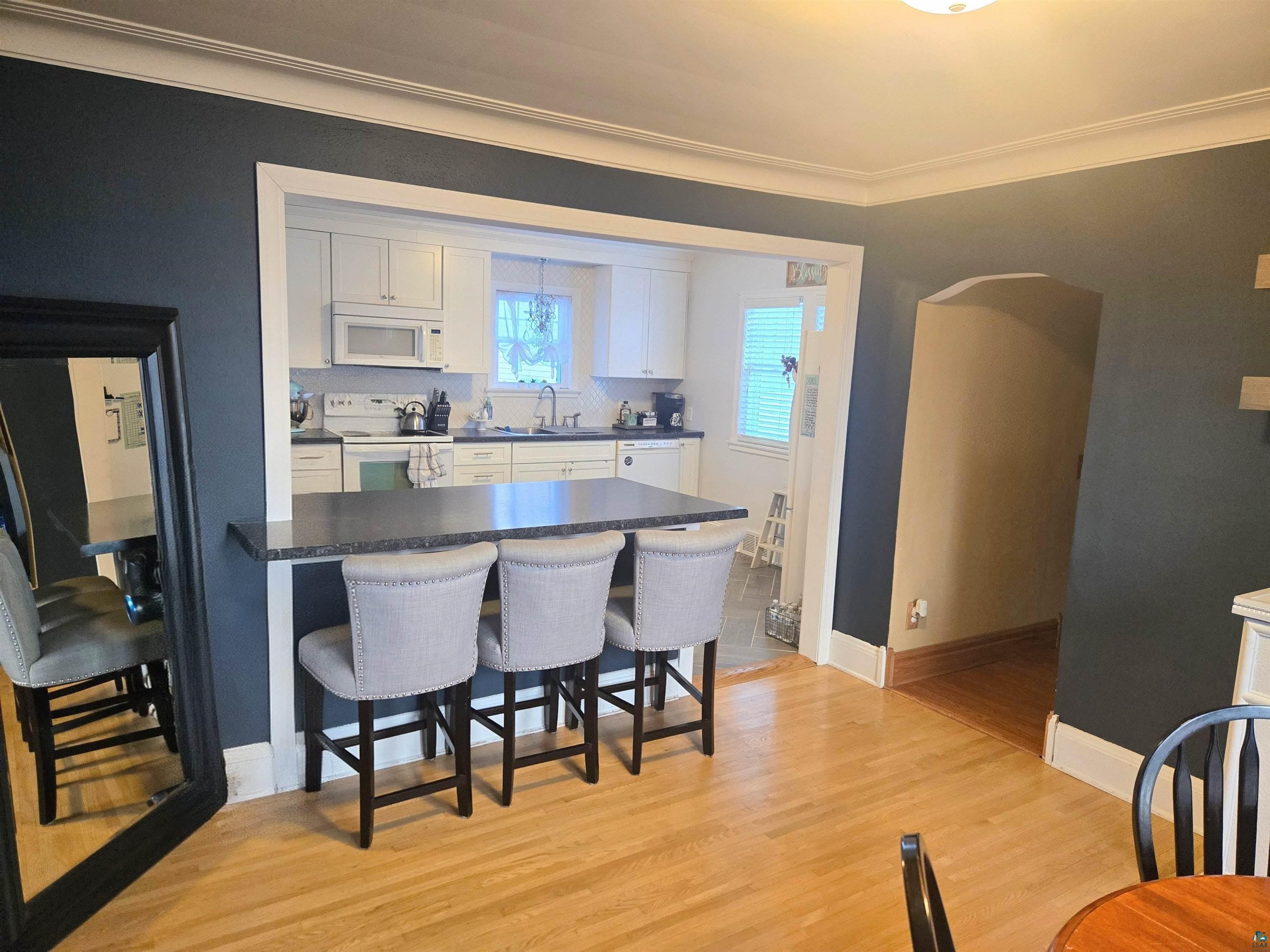 4327 West 5th Street Duluth, MN 55807 - Photo 12 of 25 Kitchen with a kitchen breakfast bar, white appliances, white cabinets, light wood-type flooring, and arched walkways