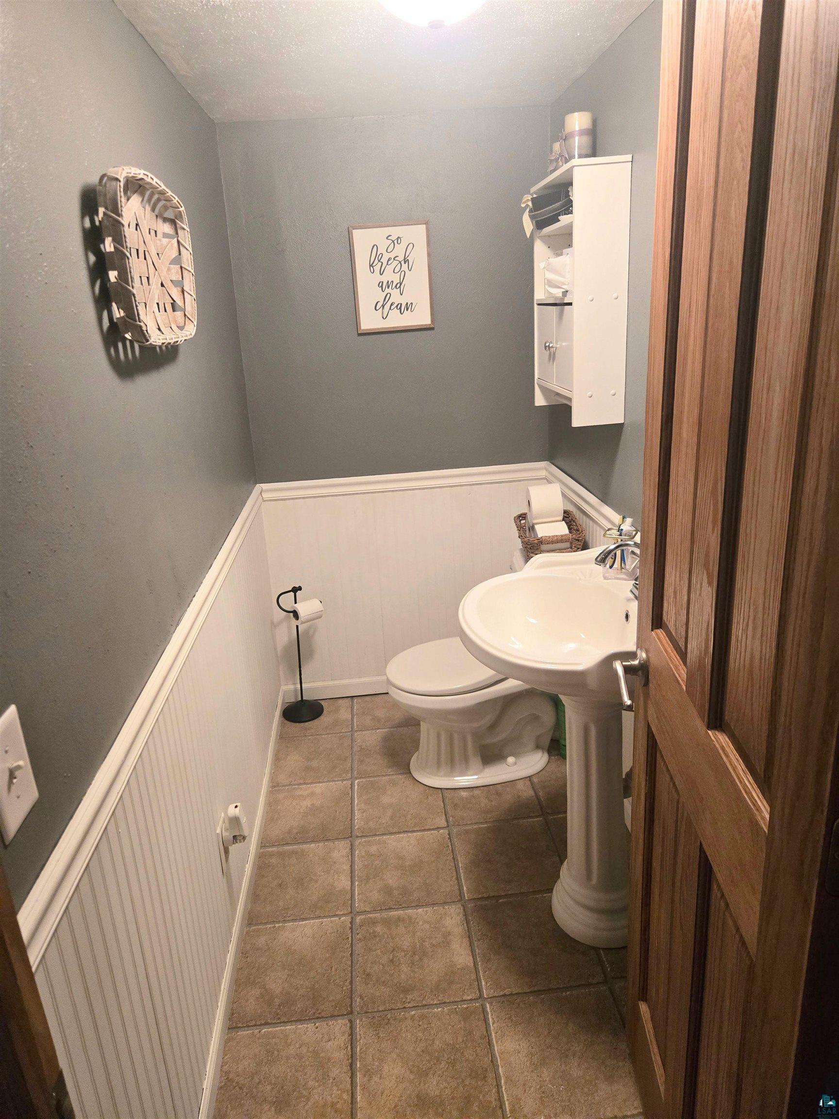 4327 West 5th Street Duluth, MN 55807 - Photo 19 of 25 Bathroom with a wainscoted wall, dark tile patterned floors, and a decorative wall