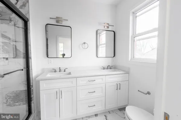 a bathroom with double vanity sink a mirror and a toilet