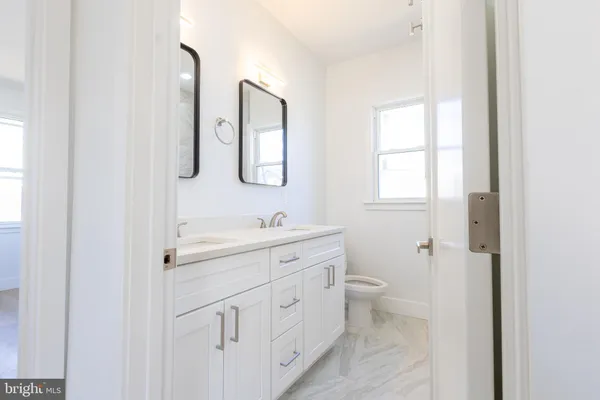 a bathroom with a double vanity sink a toilet and a window