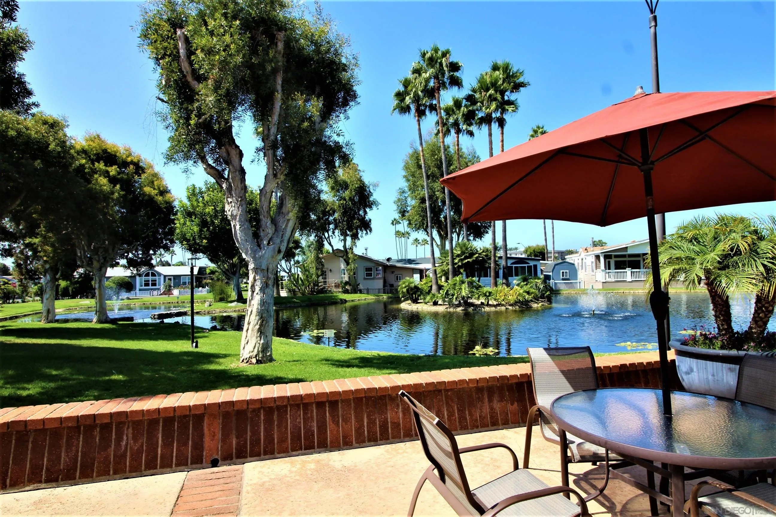 7132 Santa Rosa Carlsbad, CA 92011 - Photo 36 of 54 a patio with wooden floor a yard a table and chairs