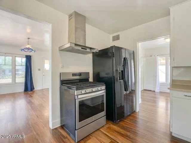 a kitchen with stainless steel appliances wooden floor and a refrigerator