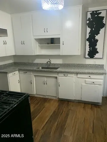 a kitchen with granite countertop a stove a sink and a microwave