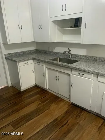 a kitchen with granite countertop white cabinets and a sink