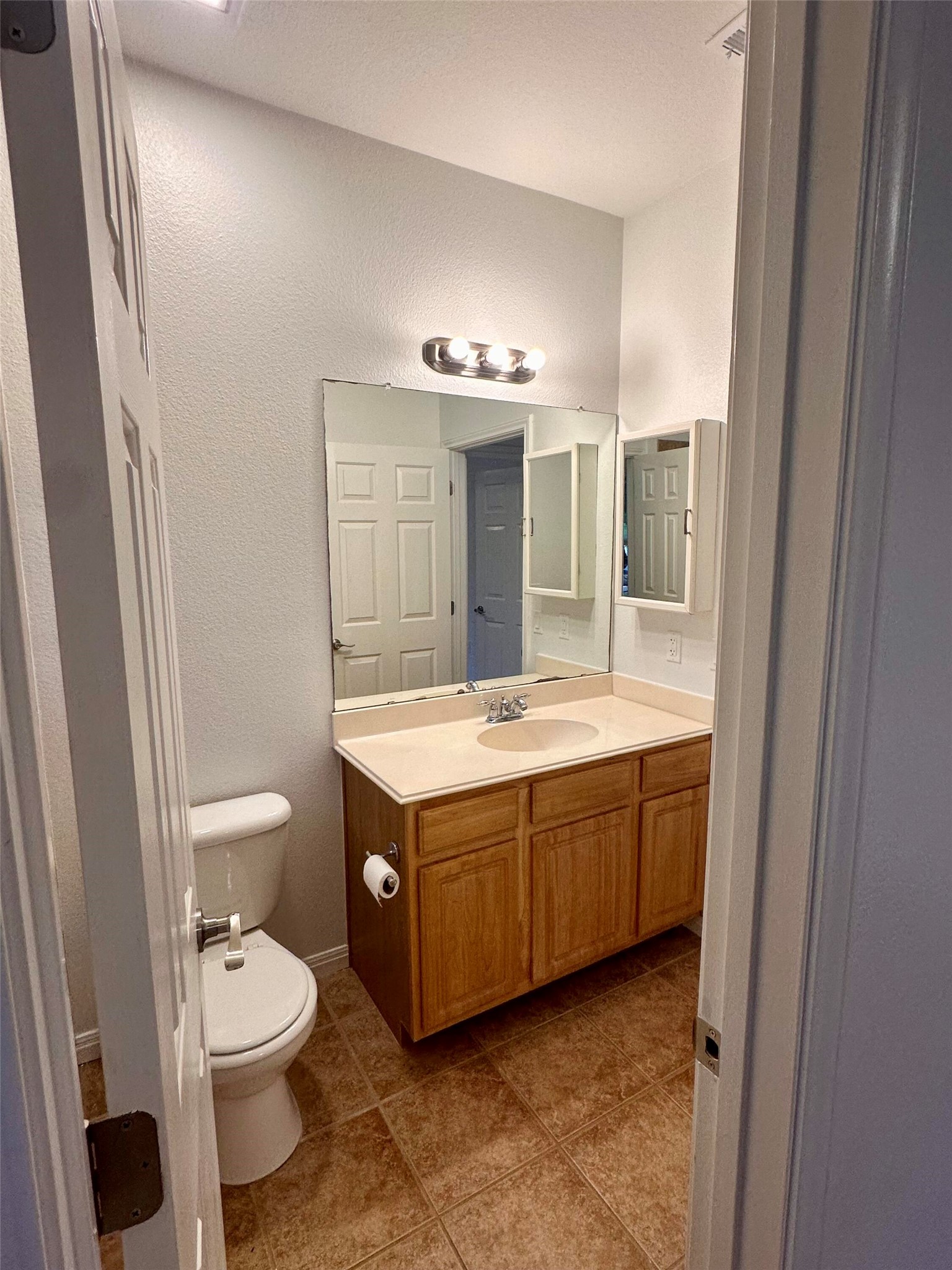 1122 Mansell Avenue Austin, TX 78721 - Photo 20 of 29 a spacious bathroom with a granite countertop toilet a sink and a mirror