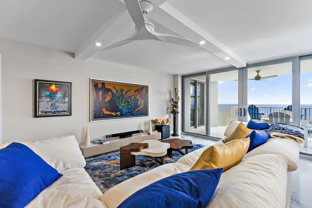 a living room with furniture kitchen view and a large window