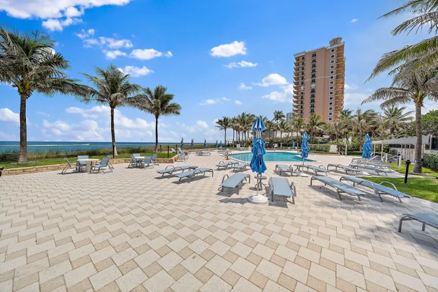 a view of a swimming pool with a lounge chair and palm trees