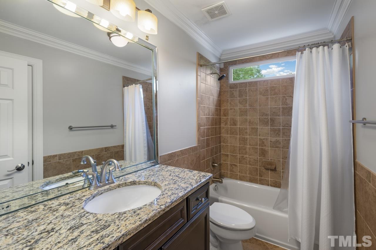 4401 Touchstone Forest Road Raleigh, NC 27612 - Photo 29 of 44 a bathroom with a granite countertop sink a toilet a mirror a bathtub and shower