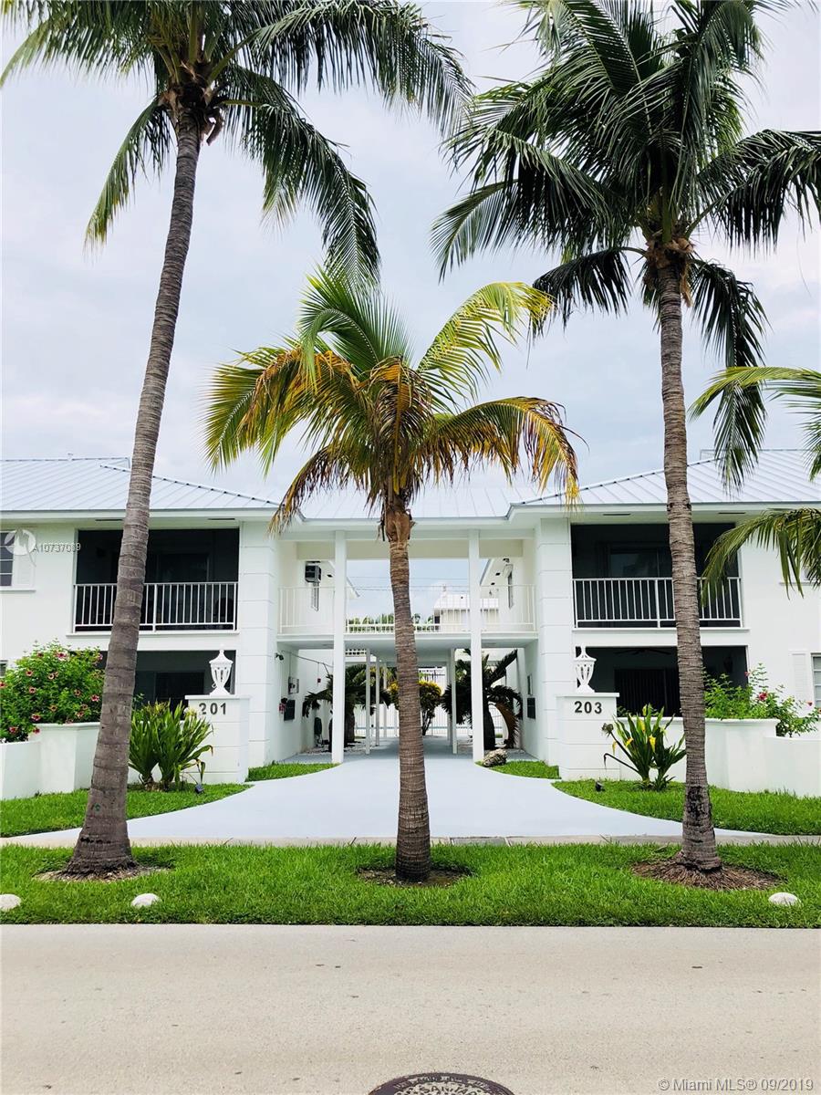 a front view of multiple houses with yard and green space