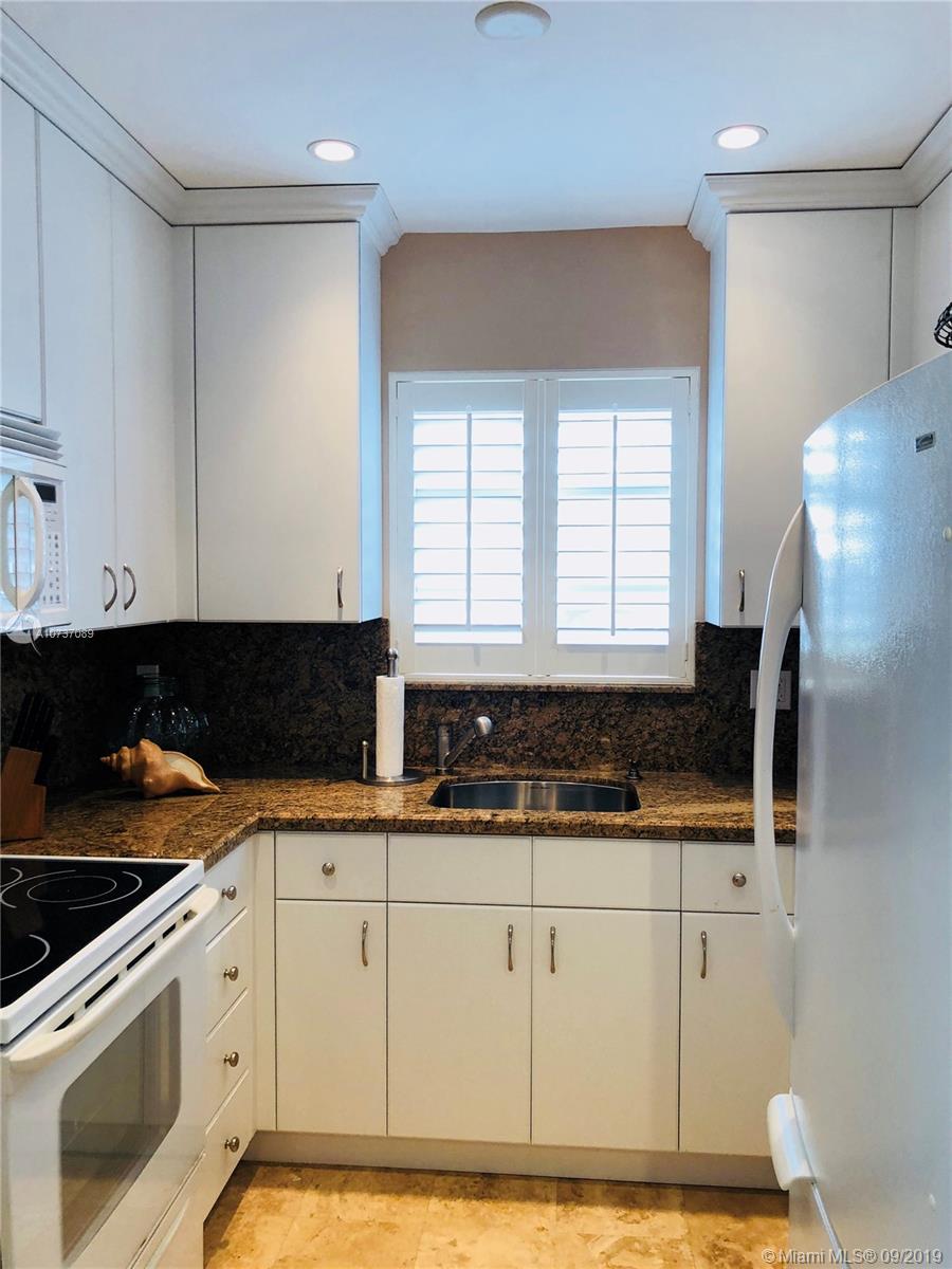 201 Sunrise Drive, Unit 109 Key Biscayne, FL 33149 - Photo 6 of 14 a kitchen with granite countertop a sink a stove and cabinets