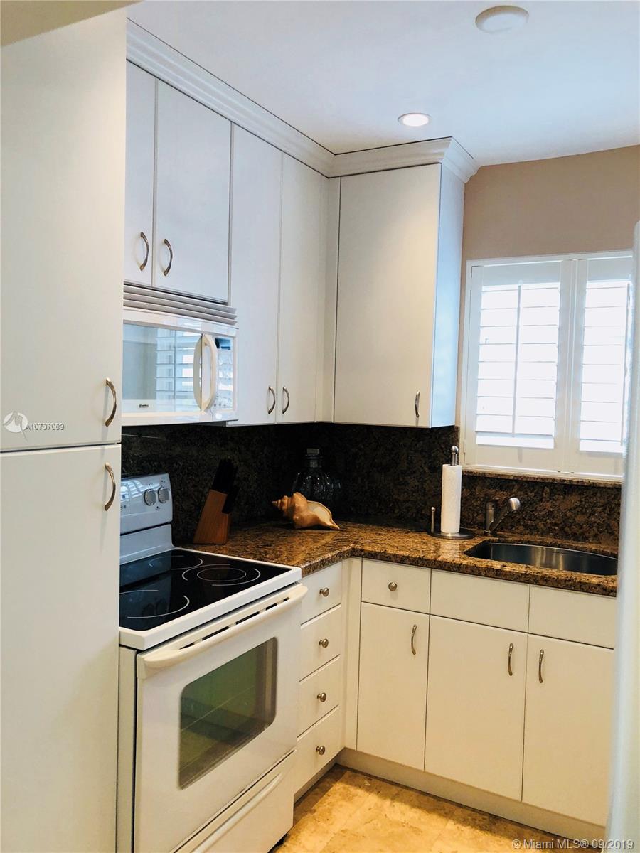 201 Sunrise Drive, Unit 109 Key Biscayne, FL 33149 - Photo 7 of 14 a kitchen with white cabinets and appliances