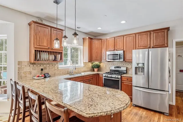 a kitchen with stainless steel appliances granite countertop a refrigerator a sink dishwasher a stove a dining table and chairs with wooden floor