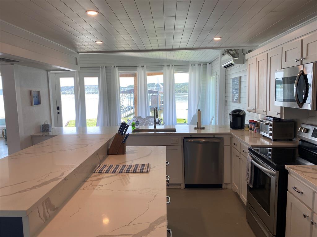 4415 Chapel Road Graham, TX 76450 - Photo 31 of 40 a large kitchen with kitchen island a stove a sink dishwasher a dining table and wooden floor