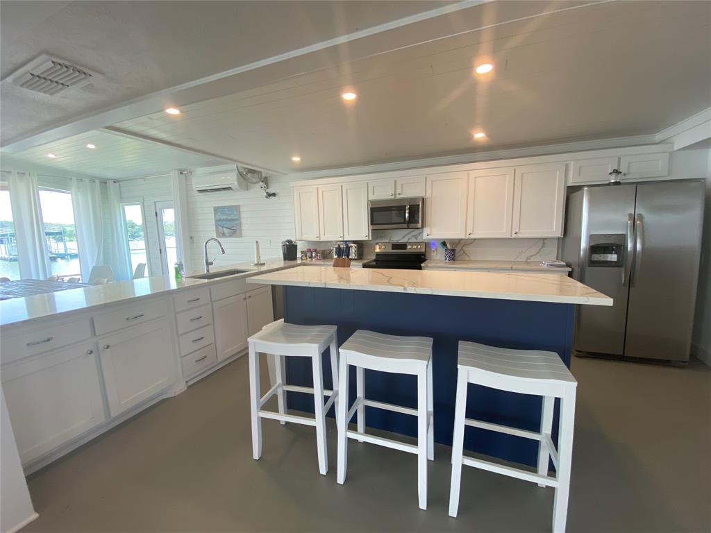4415 Chapel Road Graham, TX 76450 - Photo 32 of 40 a kitchen with stainless steel appliances a sink a stove a refrigerator with white cabinets and wooden floor