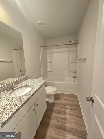 a bathroom with a granite countertop sink a toilet and shower
