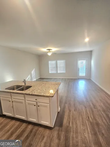 a kitchen with granite countertop a stove a sink and wooden floor