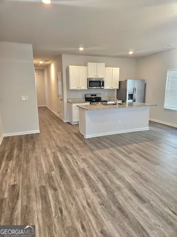 a large kitchen with kitchen island a sink dishwasher a refrigerator and a stove with wooden floor