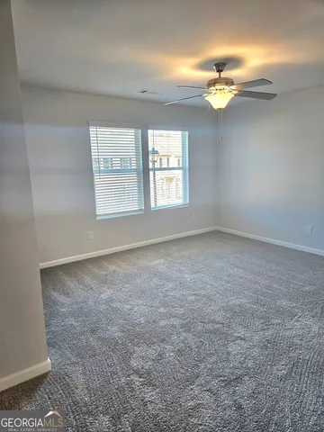 an empty room with a chandelier fan and windows