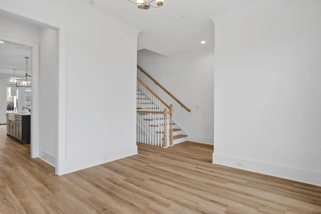 an empty room with wooden floor fireplace and a kitchen view