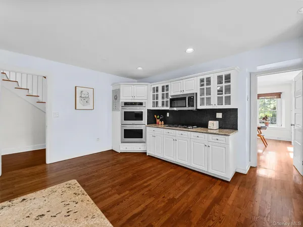a large white kitchen with kitchen island a stove a refrigerator a sink and a stove with wooden floor