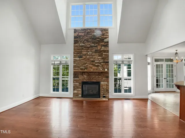 an empty room with wooden floor fireplace and windows