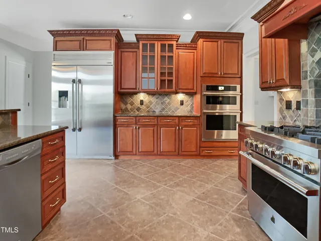 a kitchen with stainless steel appliances granite countertop a stove top oven a sink and a refrigerator