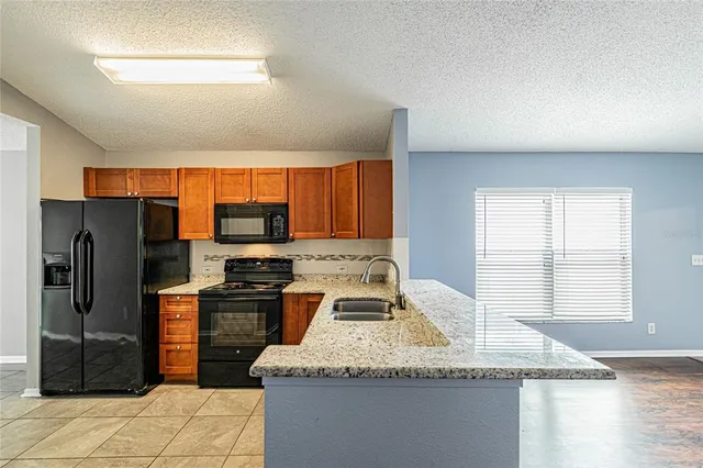 a kitchen with granite countertop stainless steel appliances a sink counter space and a window