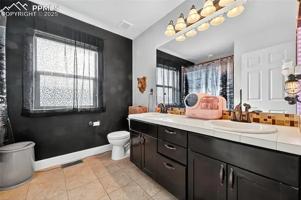 a spacious bathroom with a double vanity sink toilet mirror and window