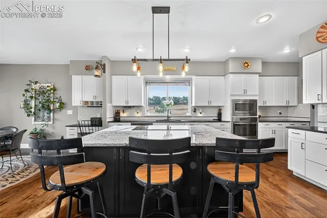 a kitchen with stainless steel appliances a dining table chairs stove and white cabinets