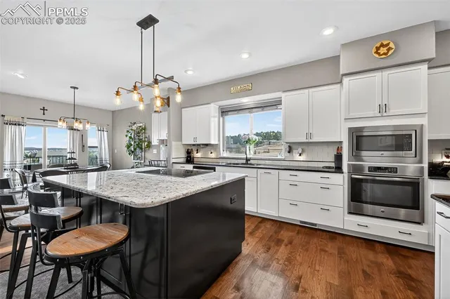 a kitchen with stainless steel appliances kitchen island a table chairs in it and wooden floors