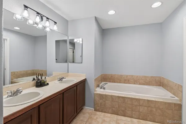 a bathroom with a tub a sink and mirror