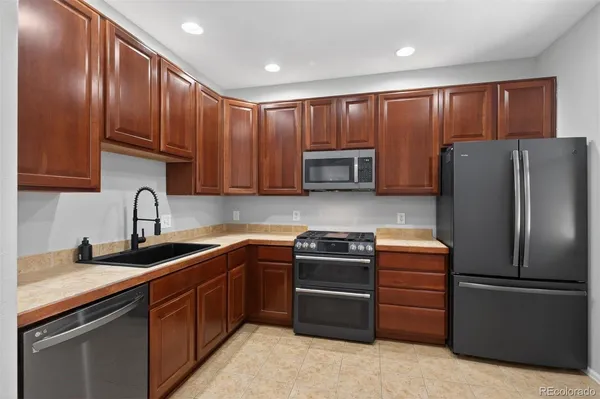 a kitchen with stainless steel appliances granite countertop a refrigerator stove a sink and dishwasher a oven with wooden cabinets