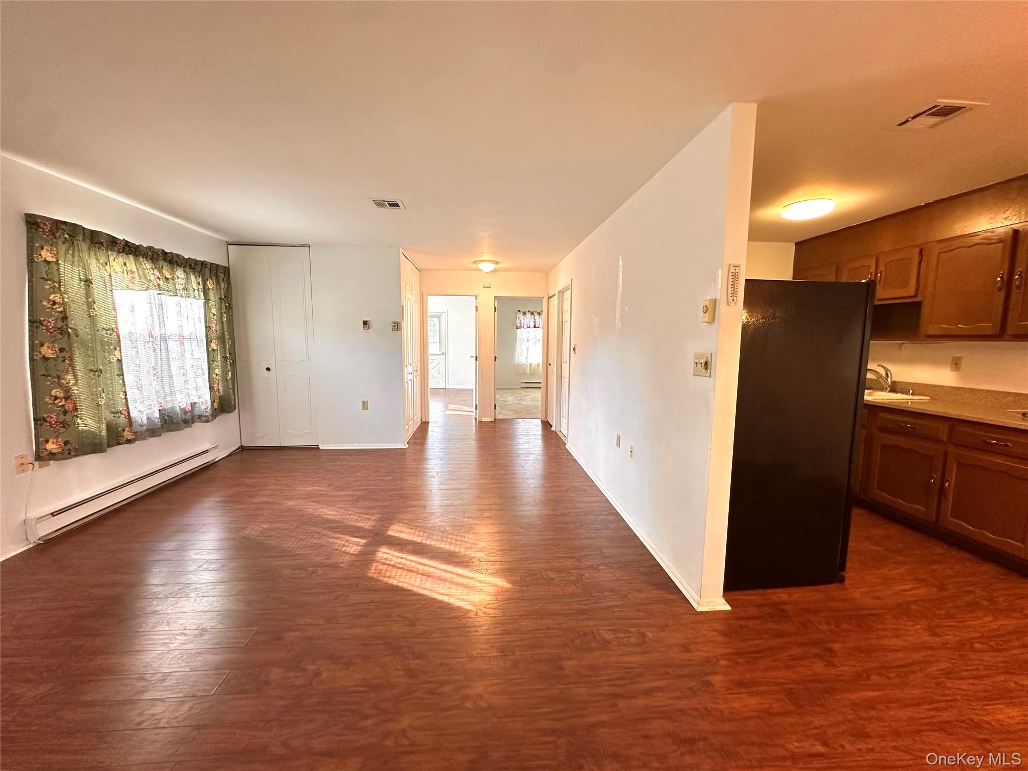 169 Ventry Court, Unit A Ridge, NY 11961 - Photo 6 of 17 a view of a refrigerator in kitchen and an empty room with wooden floor