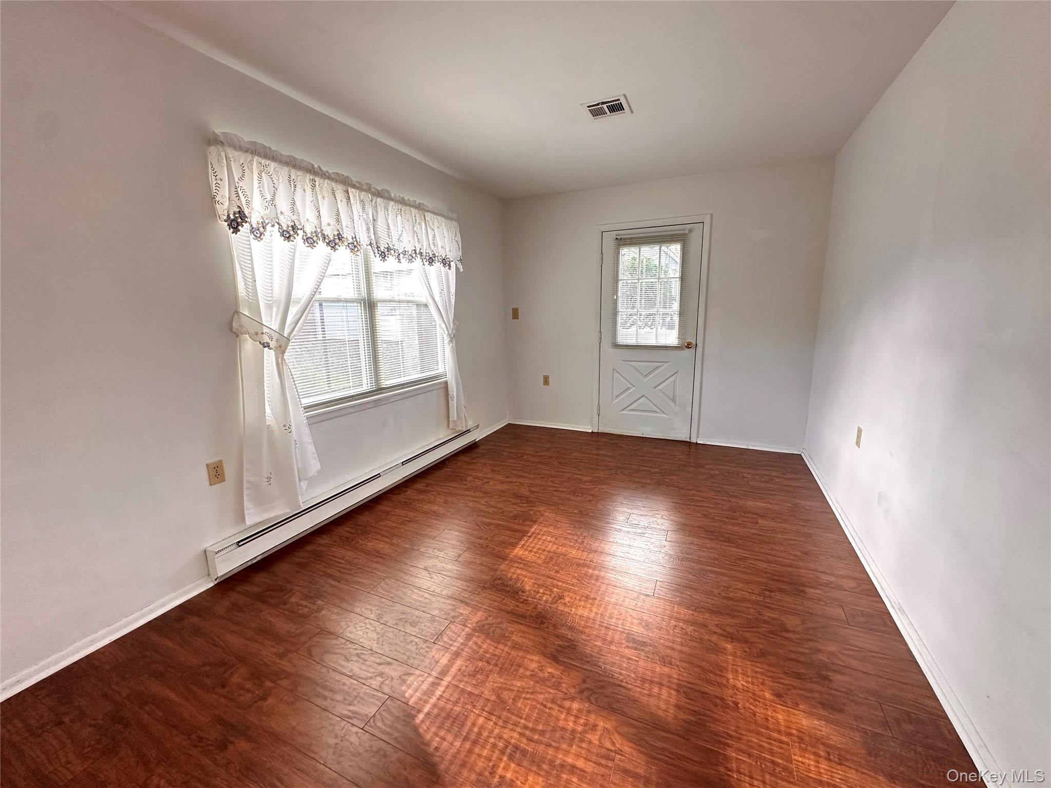169 Ventry Court, Unit A Ridge, NY 11961 - Photo 10 of 17 an empty room with wooden floor and windows