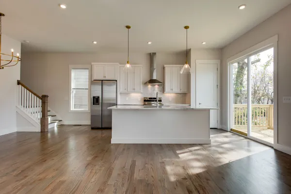 a view of kitchen with stainless steel appliances granite countertop wooden floor sink and a window