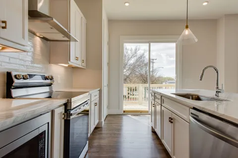 a kitchen with stainless steel appliances granite countertop a sink a stove and a wooden floors