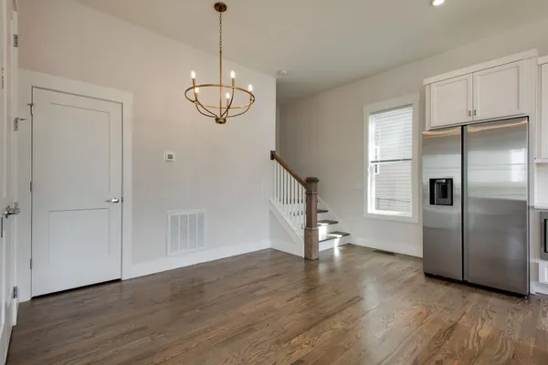 a view of an empty room with wooden floor entryway and a kitchen