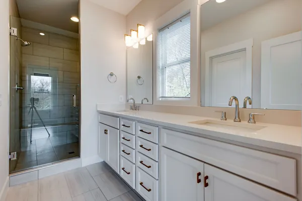 a bathroom with a double vanity sink mirror and shower