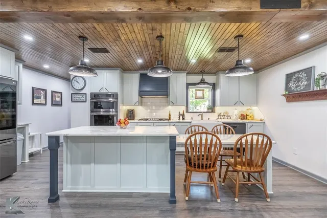 a kitchen with stainless steel appliances granite countertop a table chairs and a wooden floor
