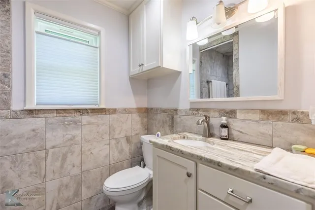 a bathroom with a granite countertop toilet sink and mirror