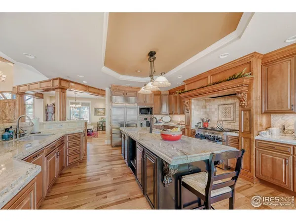 a kitchen with stainless steel appliances granite countertop a stove a sink dishwasher and a refrigerator with wooden floor