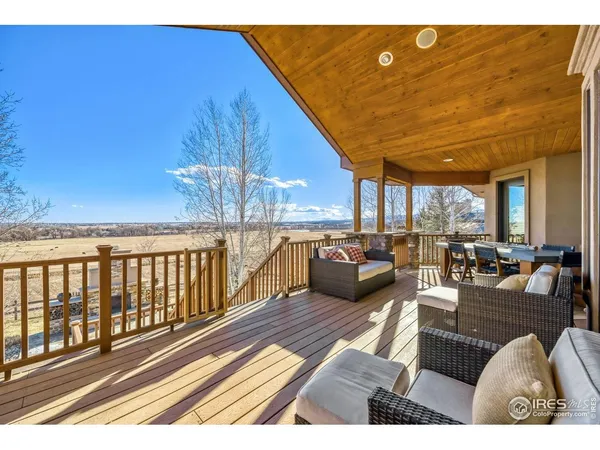 a view of a dining room and livingroom with furniture wooden floor a rug a flat screen tv a painting and a chandelier