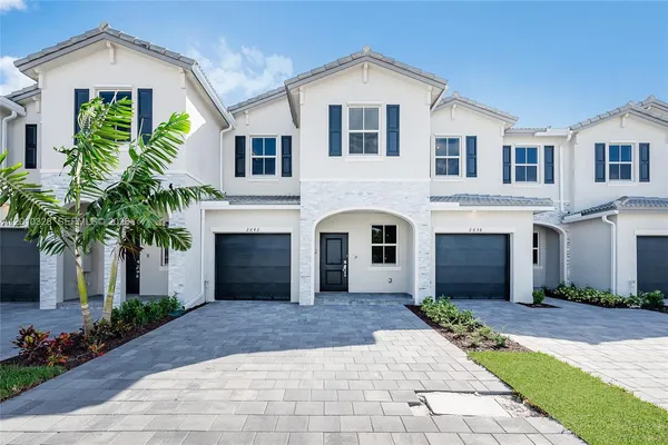 a front view of a house with yard and parking